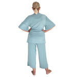 Person wearing a sage green surgery recovery pajama set on a white background from backside